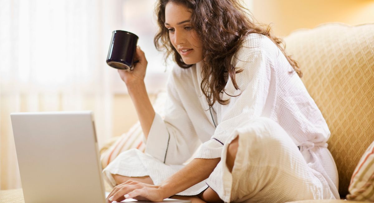 A person reviewing plumbing service estimates on a laptop at home with a coffee cup in hand.