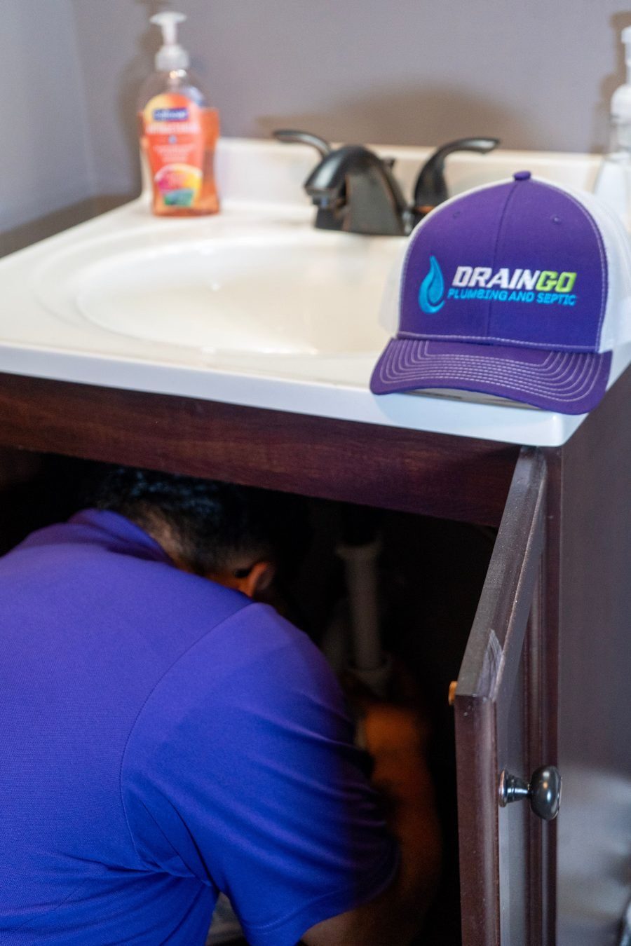 plumber working under bathroom sink