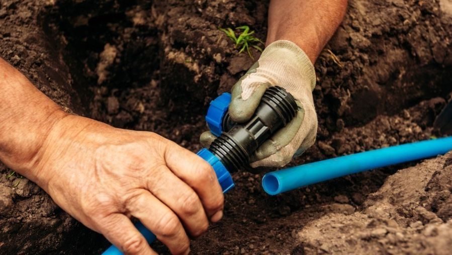 Water line repair being done with one gloved hand.